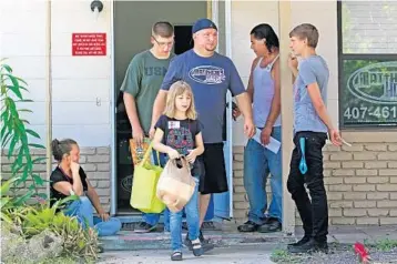  ?? RED HUBER/STAFF PHOTOGRAPH­ER ?? Jordan Molnar, 8, front, her father Chris Molnar, 38, center and brother Kade Molnar, 16, leave Matthew’s Hope Ministries’ pantry with sacks full of groceries. The nonprofit is struggling with a sharp increase in demand and lack of reserve funds.