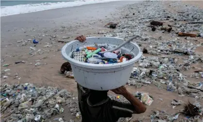  ?? Photograph: Agung Parameswar­a/Getty Images ?? A woman collects recyclable plastics washed up on the beach in Bali, Indonesia.