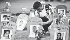  ??  ?? A man arranges tombstones with pictures of dead protesters during a prayer for Venezuelan TV news network Globovisio­n’s kidnapped journalist, Nairobi Pinto, in Caracas. — AFp photo