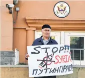  ??  ?? A man holds a banner supporting Syria and read as "Putin is right!" in front of US embassy in central Moscow on Saturday. The UN Security Council will meet on Saturday at Russia's request to discuss air strikes launched by the United States, France and...