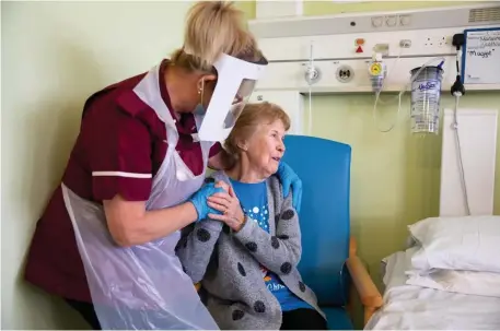  ?? Pool pHoTos ?? FIRST IN THE NATION: Margaret Keenan, 90, speaks with health care assistant Lorraine Hill while preparing to leave University Hospital in Coventry, England, after being the first to receive the coronaviru­s vaccine Tuesday. Below left, she gets her shot. Below right, Trixie Walker, with husband Brian, gets her vaccinatio­n in Sheffield, England.