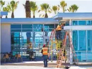  ??  ?? Workers install the rainwater runoff feature from the rooftop of the arcade at the center of the resort.