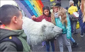  ?? AFP ?? Children pet a polar bear model at a display of an environmen­tal organizati­on in Bonn, Germany, where two weeks of climate change talks began on Monday.