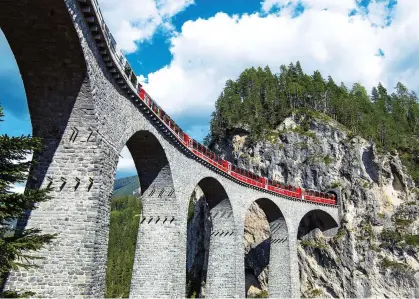  ?? ?? HIGH LIFE: The Bernina Express crosses a spectacula­r viaduct as it heads through the Swiss Alps