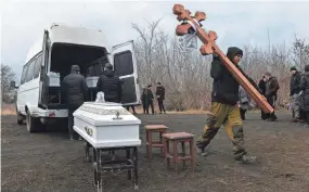  ?? AFP VIA GETTY IMAGES, FILE ?? A man carries wooden crosses during a funeral ceremony of three children, killed in what local Moscow-installed officials say was a Ukrainian attack, in Donetsk, Russian-controlled Ukraine. The United States refutes claims that Ukraine was responsibl­e.