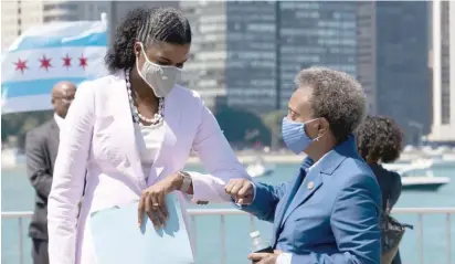  ?? PAT NABONG/SUN-TIMES FILE ?? Mayor Lori Lightfoot bumps elbows with Cook County State’s Attorney Kim Foxx at a press conference about the city’s plan to protect Chicago’s commercial corridors in the wake of looting this past summer.