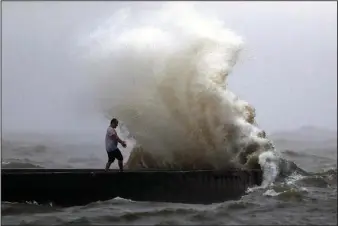 ?? The Associated Press ?? LOUISIANA COAST: A wave crashes as a man stands on a jetty near Orleans Harbor in Lake Pontchartr­ain in New Orleans on Sunday as Tropical Storm Cristobal approaches the Louisiana Coast.