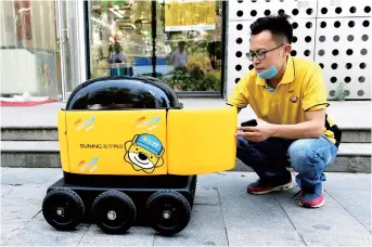  ??  ?? A Suning worker loads a delivery robot with groceries during a demonstrat­ion of the robot in Beijing. Along a quiet residentia­l street, a yellow and black cube about the size of a small washing machine trundles leisurely to its destinatio­n. — AFP