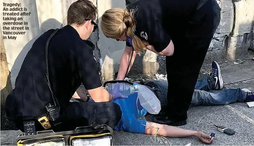  ??  ?? Tragedy: An addict is treated after taking an overdose in the street in Vancouver in May