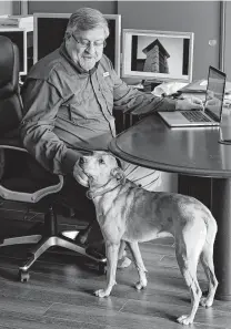  ?? Michael Wyke / Contributo­r ?? J.T. Burk pets his dog, Ellie, at his home office in Houston. The 67-year-old architect is still able to work despite living with Stage 4 colorectal cancer.