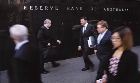 ??  ?? Business people walk outside the Reserve Bank of Australia in Sydney. The central bank predicts the Australia’s economy will expand at a 3%-plus pace this year and next, but also concedes that dangers are mounting.