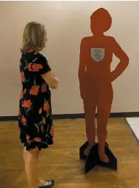  ??  ?? Jennifer Mitchell, an attendee of The Silent Project event, reads the message of a silent witness victim of domestic violence. The red silhouette­s represent a person whose life ended at the hands of a partner or ex-partner.