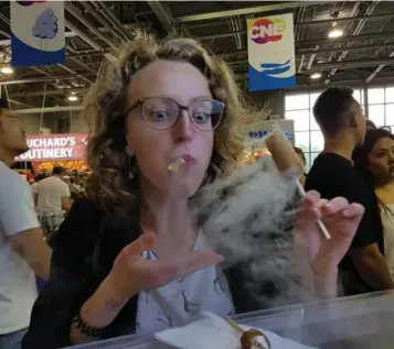  ?? LAURA HOWELLS/TORONTO STAR ?? Laura Howells tries the Dragon Breath ice cream crepes at the CNE. The $10 treats are dipped in liquid nitrogen.