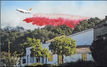  ?? Noah Berger The Associated Press ?? An air tanker drops retardant behind the Newhall Church of the Nazarene while battling the Saddleridg­e Fire in Newhall, Calif., on Friday.