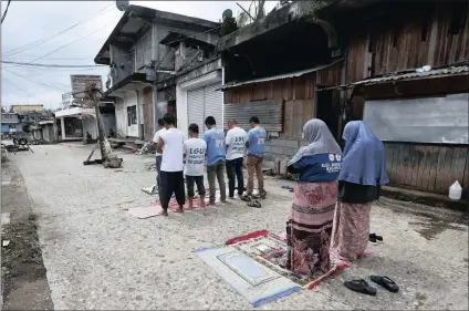  ?? PICTURE: AP ?? Volunteers pray in the middle of an abandoned street as they take part in a massive clean-up in Marawi, southern Philippine­s, yesterday after being cleared of Islamic State group-linked militants.