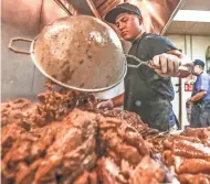  ??  ?? Diego De Leon places carnitas on a cart before their two busiest days, Saturday and Sunday at Carnitas Don Lucho in Milwaukee. They serve 1,500 pounds of carnitas to people over a weekend, and the lines form in early morning on Milwaukee’s south side.