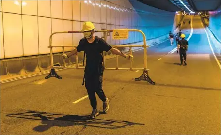  ?? Billy H.C. Kwok Getty Images ?? A DEMONSTRAT­OR moves a barricade after a march against a now-suspended extraditio­n bill amid ongoing protests in Hong Kong.