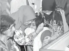  ??  ?? Rohani (second left) consoling D. Shanti when paying her last respects to T Nhaveen. — Bernama photo