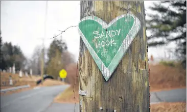  ?? JESSICA HILL / THE NEW YORK TIMES ?? A green, chalkboard-like heart, a small remembranc­e of the mass shooting at Sandy Hook Elementary, is nailed to a utility pole in Newtown, Conn.