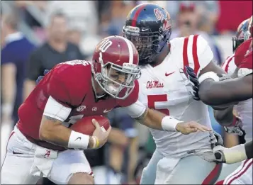  ?? BUTCH DILL / ASSOCIATED PRESS ?? Alabama quarterbac­k AJ McCarron scrambles from pressure by Ole Miss freshman defensive end Robert Nkemdiche, one of numerous freshmen getting plenty of playing time for Ole Miss, as well as Saturday opponent Auburn.