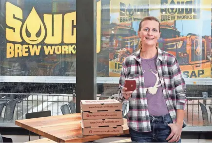  ?? BARBARA J. PERENIC/COLUMBUS DISPATCH ?? Jamie Young raises a glass at Saucy Brew Works’ new location on West 3rd Avenue in Columbus. The 190-seat space has indoor and outdoor seating along with a small brewery.