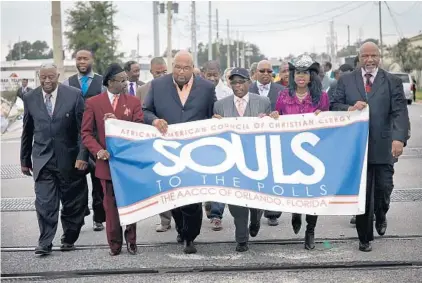  ?? JACOB LANGSTON/ORLANDO SENTINEL ?? Rev. Randolph Bracy, Jr, right, and other church leaders and members march down Kaley Street in Orlando on their way to early vote on October 28, 2012. Members from about 20 churches gathered at the Orange County Supervisor elections office to cast their vote early.