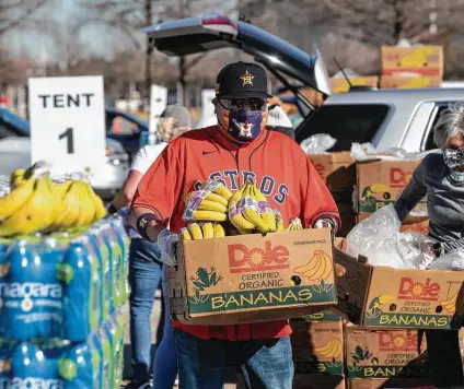  ?? Brett Coomer / Staff photograph­er ?? Chris Wiggin carries a box of bananas to hand out during a food distributi­on event by the Houston Food Bank on Feb. 23.