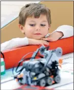  ??  ?? Thomas Torres, 3, watches one of the robots at the “Gear Guys” table at a robotics expo Sunday.