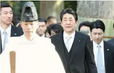  ?? - Reuters ?? Prime Minister Shinzo Abe is led by a shinto priest during a customary New Year’s visit at Ise shrine in Ise, in this photo taken by Kyodo on Thursday.