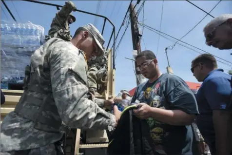  ?? CARLOS GIUSTI - THE ASSOCIATED PRESS ?? National Guardsmen arrive at Barrio Obrero in Santurce to distribute water and food among those affected by the passage of Hurricane Maria, in San Juan, Puerto Rico, Sunday. Federal aid is racing to stem a growing humanitari­an crisis in towns left...