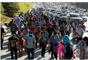  ?? AP ?? Migrants traveling in a group begin their journey toward the U.S. border as they walk along a highway in San Salvador, El Salvador. Some cite poverty and rampant gang violence at home for their need to flee.