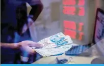  ?? — AFP ?? ISTANBUL: A teller holds Turkish lira banknotes at a currency exchange office in Istanbul yesterday.