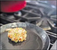  ?? BRYAN MELTZ/ THE NEW YORK TIMES ?? The char burger, from a recipe in Alton Brown’s new book, uses 1 pound boneless, skinless arctic char fillets, panko breadcrumb­s, scallions, bell peppers, an egg, wasabi and spices. The patties are placed on onion buns.