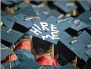  ?? AJC FILE ?? A college student puts a job plea on his graduation cap, reflecting a pragmatic approach to higher ed.