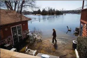  ?? AP/Omaha World-Herald/BRENDAN SULLIVAN ?? Lori Steinauer walks through a patio area at her flooded cabin Thursday in Ashland, Neb.