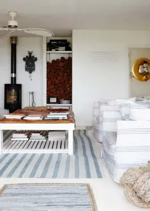  ??  ?? LIVING ROOM The clean-cut design of the woodburner and woodstore paired with simple striped linens and rugs reflect Caryl’s unfussy yet cosy ethos