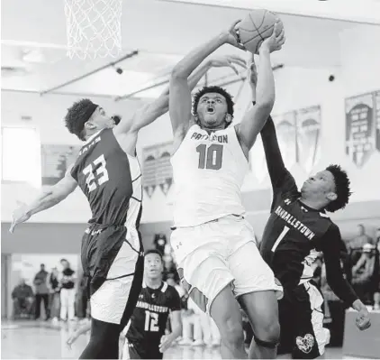  ?? KIM HAIRSTON/BALTIMORE SUN ?? Sophomore Marvin Price scores despite the defense of Randallsto­wn’s John McNeal (23) and Ose Okojie (1) during Patterson’s victory in Saturday’s Class 2A North Region title game. Price scored 19 points in the second quarter and finished with 28.