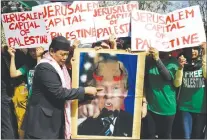  ?? AP PHOTO ?? A Muslim protester plays with a portrait of U.S. President Donald Trump with horns and fangs as they try to march toward the Israel Embassy to protest against Trump’s decision to recognize Jerusalem as the capital of Israel in metropolit­an Manila.
