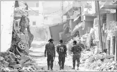  ?? — AFP photo ?? Members of the Syrian Democratic Forces walk in the former Islamic State stronghold of Raqa, as the Syrian fighters backed by US special forces battle to clear the last remaining jihadists holed up in the city.