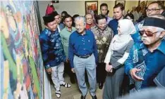  ??  ?? DR Mahathir mendengar penerangan daripada pelukis, Emma Maembong (dua dari kanan) pada majlis perasmian Gemilang Pameran Koleksi Lukisan Wajah dan Budaya Etnik Malaysia.