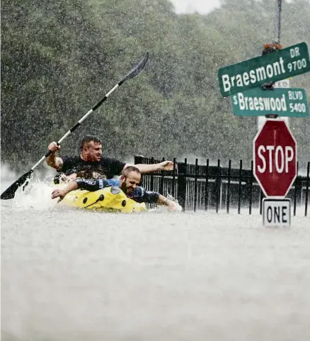  ?? KONSTANTIN­OS TSAKALIDIS / BLOOMBERG L.P. LIMITED PARTNERSHI­P ?? Dos homes, contra la corrent, durant la tormenta tropical Harvey a Houston l’agost de 2017