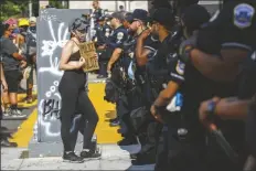  ?? ASSOCIATED PRESS ?? IN THIS JUNE 23 FILE PHOTO, a woman holds up a sign saying “police the police” as she confronts a police line while demonstrat­ors protest in Washington over the death of George Floyd. Without major changes in almost every state, a national police misconduct database like what the White House and Congress have proposed after Floyd’s death would fail to account for thousands of problem officers.