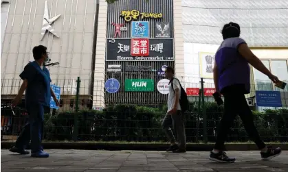  ?? García Rawlins/Reuters ?? People walk past fencing outside the Heaven Supermarke­t bar in Chaoyang district of Beijing, China, on Monday. Photograph: Carlos