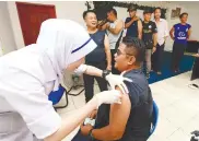  ??  ?? A National Security Council employee gets a flu shot at Sibuga Detention Centre in Sandakan on Oct 18. – BERNAMAPIX