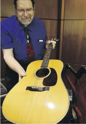  ?? L.M. OTERO/THE ASSOCIATED PRESS ?? Garry Shrum, a music memorabili­a specialist at Heritage Auctions, displays a 1963 Martin D-28 acoustic guitar that once belonged to Bob Dylan. It will be offered for sale on Nov. 11.