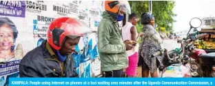  ??  ?? KAMPALA: People using Internet on phones at a taxi waiting area minutes after the Uganda Communicat­ion Commission, a body responsibl­e for communicat­ions in Uganda, restored the Internet in Kampala, Uganda, yesterday. — AFP