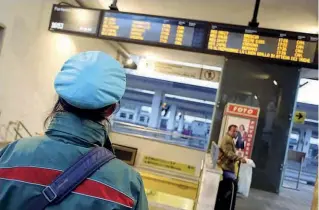  ??  ?? Centrale Una capotreno osserva il tabellone degli orari alla stazione di Treviglio, la stessa dove Beretta ha ricevuto il pugno