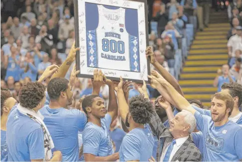  ?? | BENMCKEOWN/ AP ?? North Carolina players present coach Roy Williams with a framed jersey to commemorat­e his 800th career victoryMon­day.