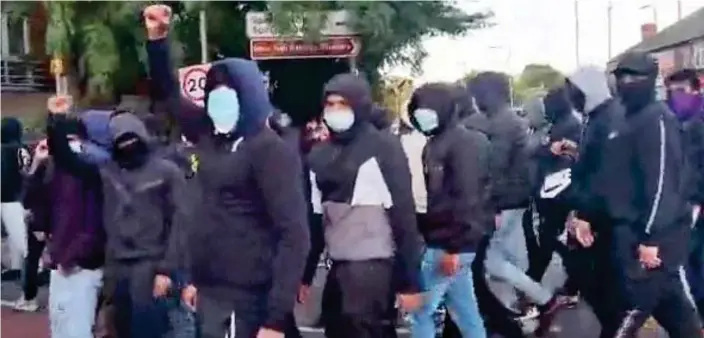  ?? ?? Mounting tension: A gang of masked and hooded men is seen marching through Leicester after a video was posted online following violent clashes in the city