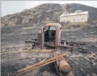  ?? CP PHOTO ?? The burned remains of a vintage truck sit in front of a house that survived a wildfire in Boston Flats, B.C., on Monday.